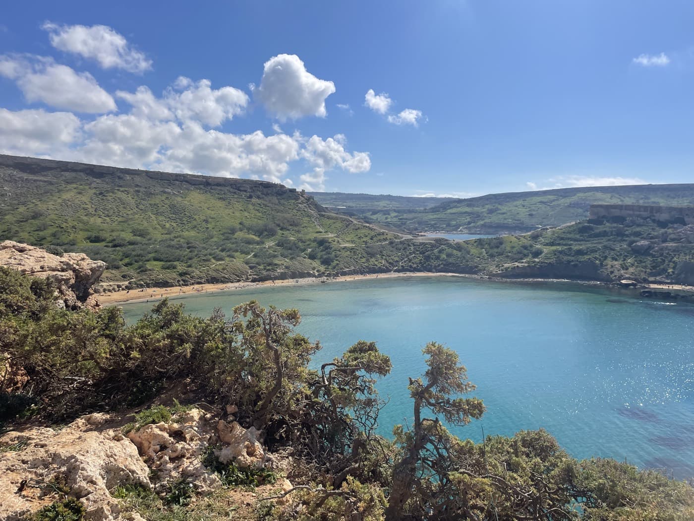 A turquoise bay ringed by green hills and pale limestone cliffs